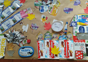Plakat leżący na stoliku przedstawia mozaike etykiet z wyrobów mlecznych i jesiennych liści.